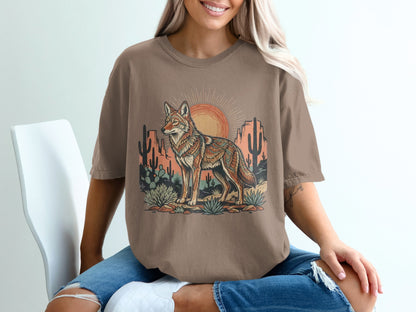 T-shirt graphic of a coyote in a desert landscape at sunset.