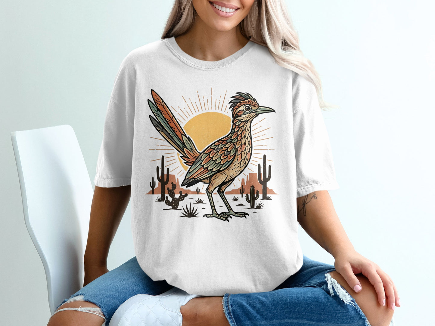T-shirt graphic featuring a roadrunner in a desert landscape with a sun and cacti.
