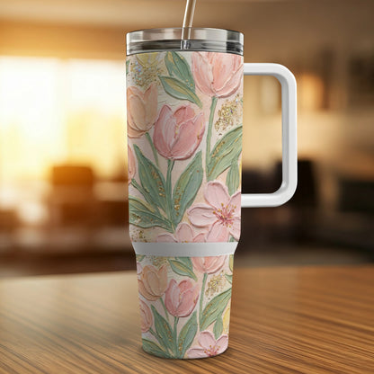 Pink floral pattern tumbler with straw and handle on wooden surface.