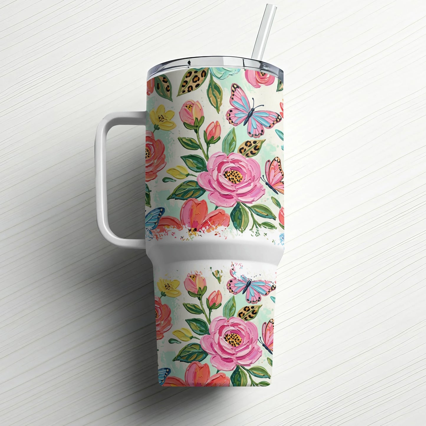Floral tumbler with handle and straw, featuring pink roses and blue butterflies.