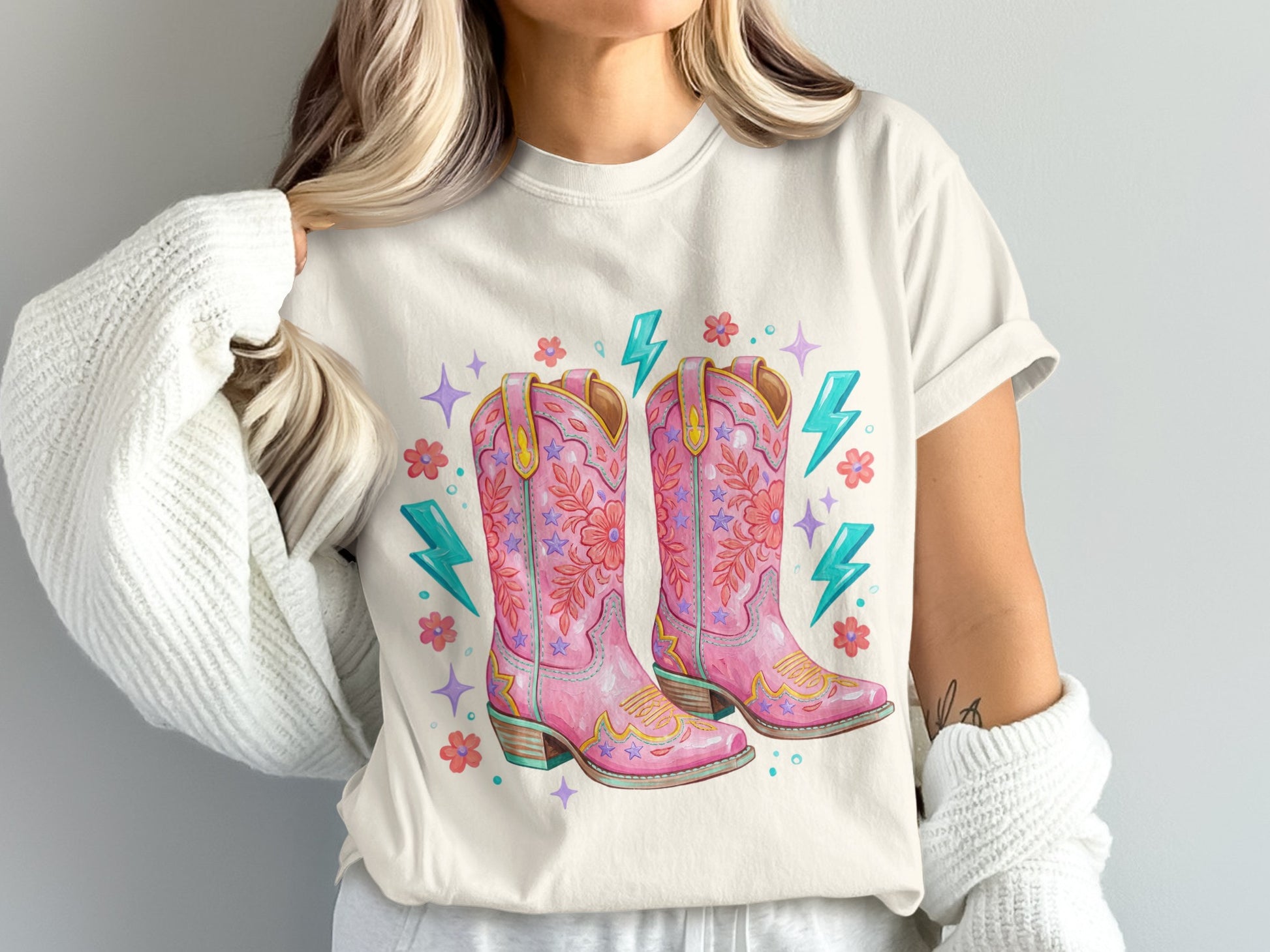 Pink cowboy boots with floral and lightning bolt accents on a t-shirt.