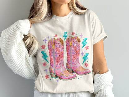 Pink cowboy boots with floral and lightning bolt accents on a t-shirt.