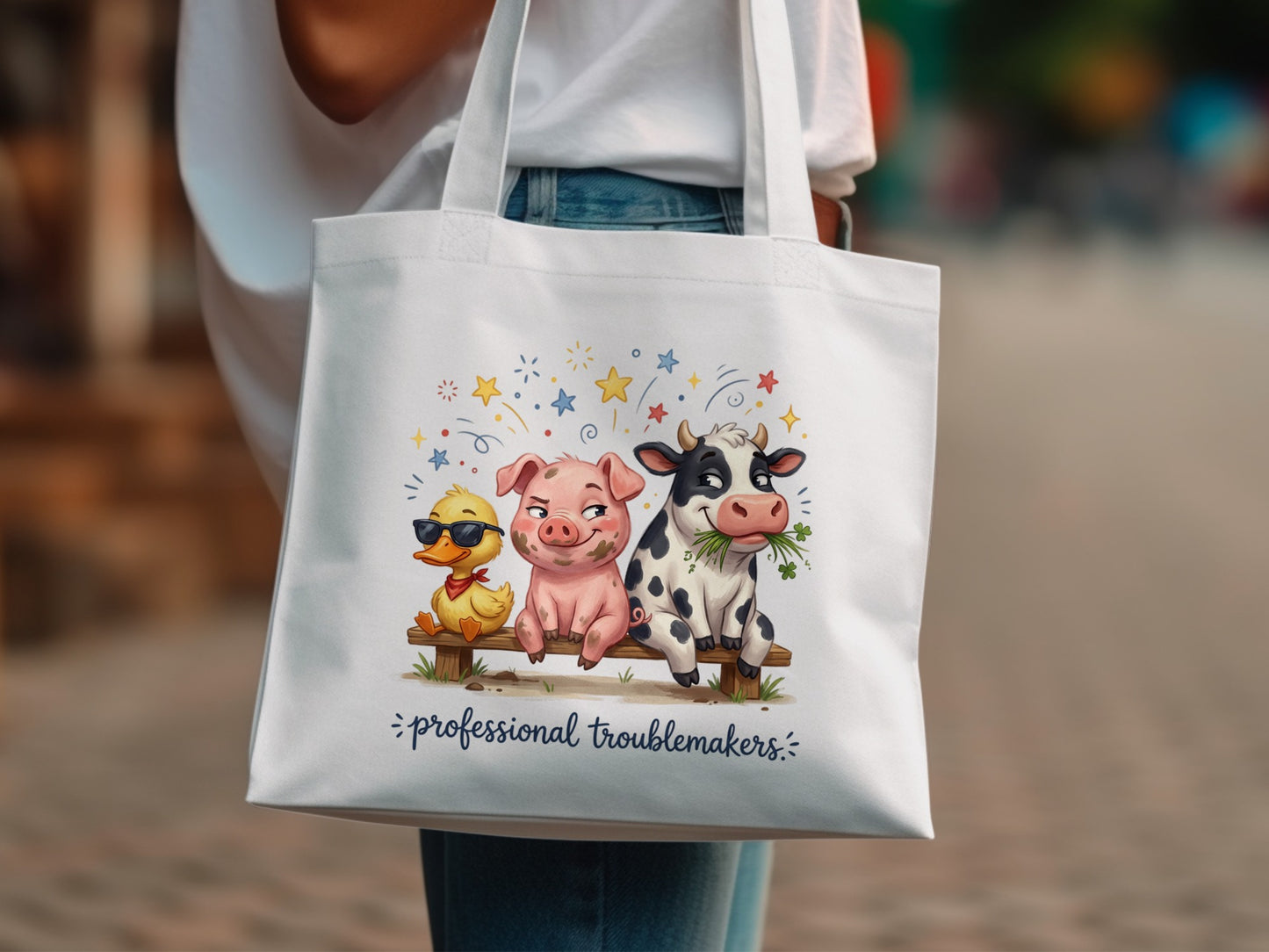 White tote bag with duck, pig, and cow illustration and text "professional troublemakers".