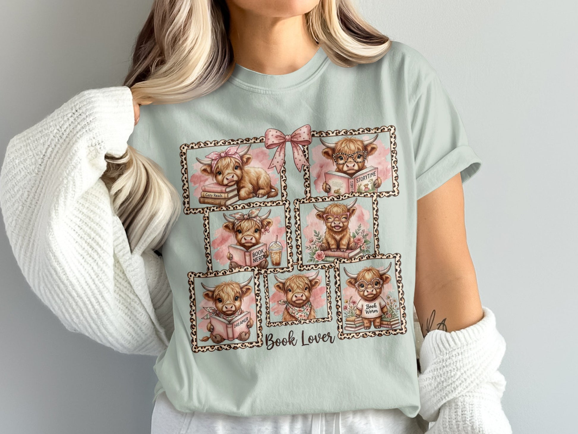 Fluffy cows reading books in framed, cute illustrations on a light blue t-shirt.