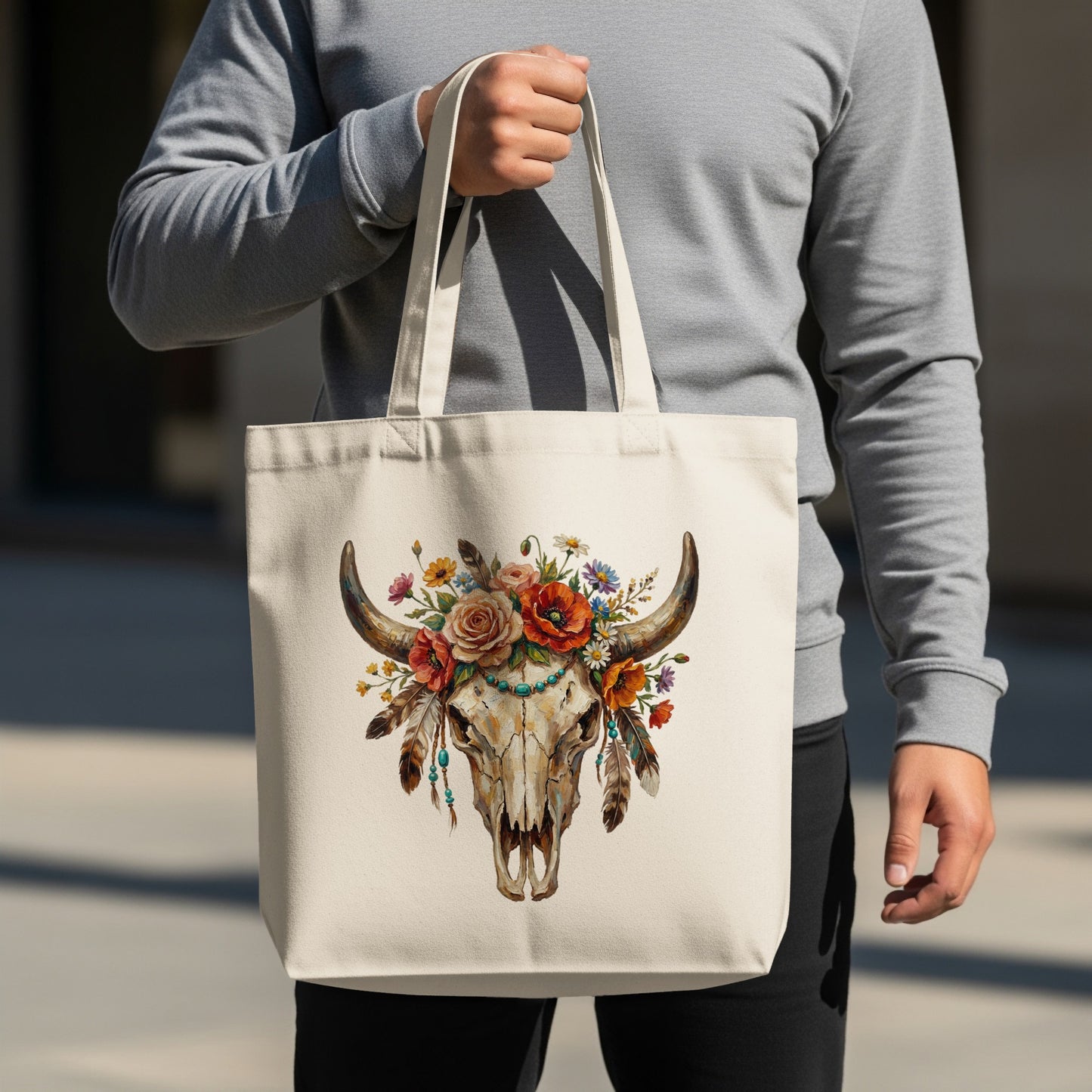 Cream tote bag with a bull skull adorned with flowers and feathers.