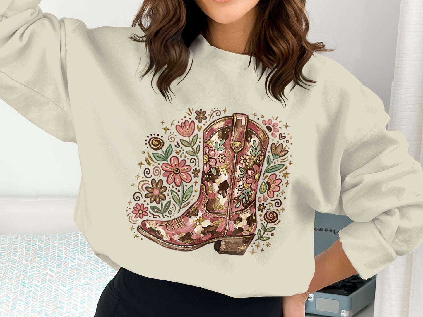 Cowboy boot with floral accents on a cream sweatshirt.