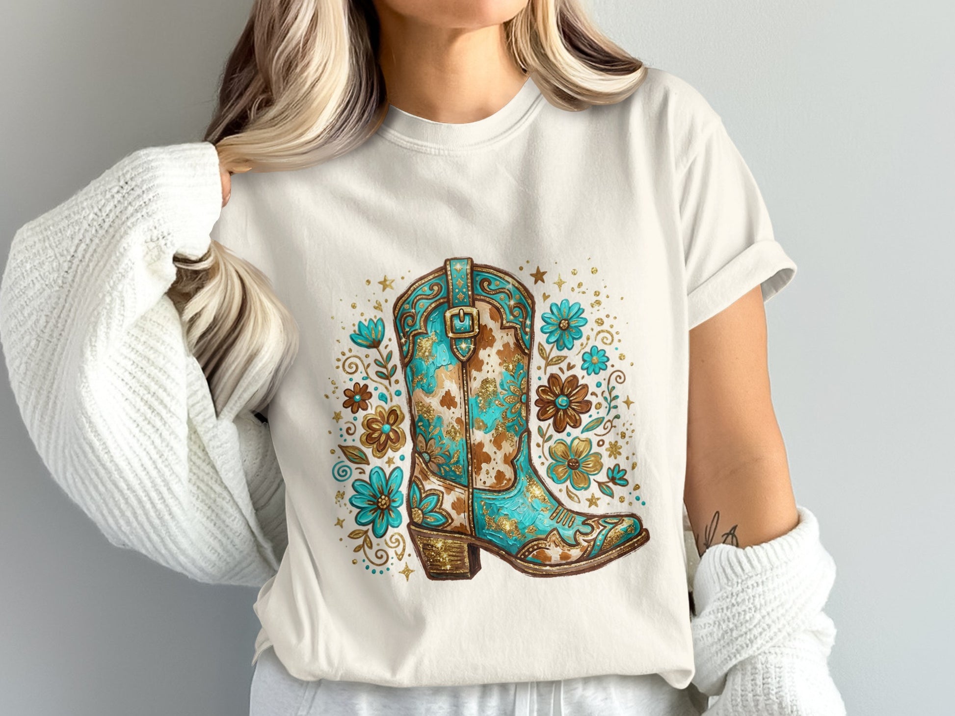 White t-shirt with a turquoise and gold floral cowboy boot design.
