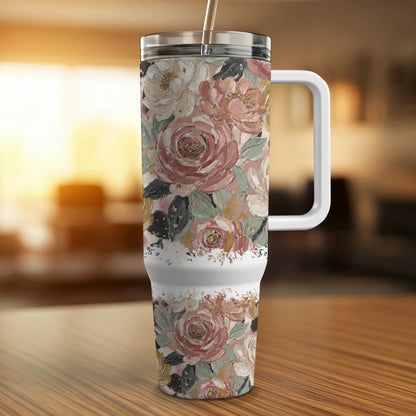 Floral-patterned tumbler with straw and handle on wooden surface.