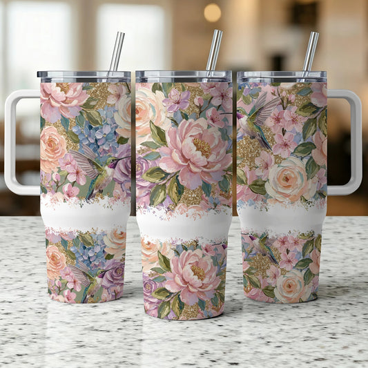 Three tumblers with floral and hummingbird designs, side by side.