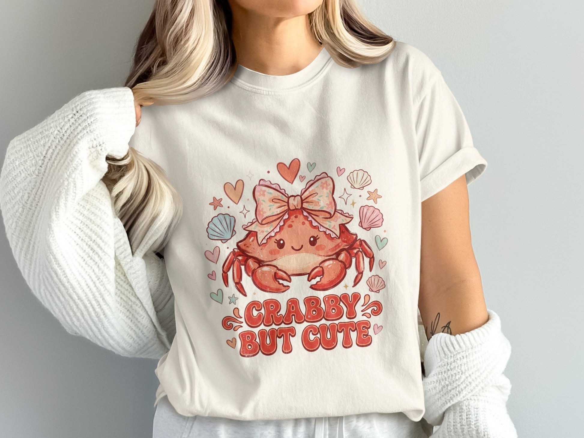 Cream t-shirt with a cartoon crab wearing a pink bow and the text "CRABBY BUT CUTE".