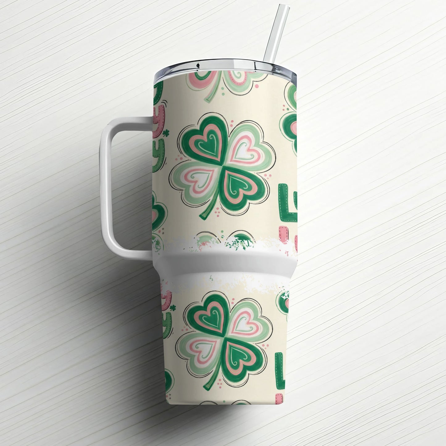 Cream tumbler with shamrock pattern and handle, straw in lid.