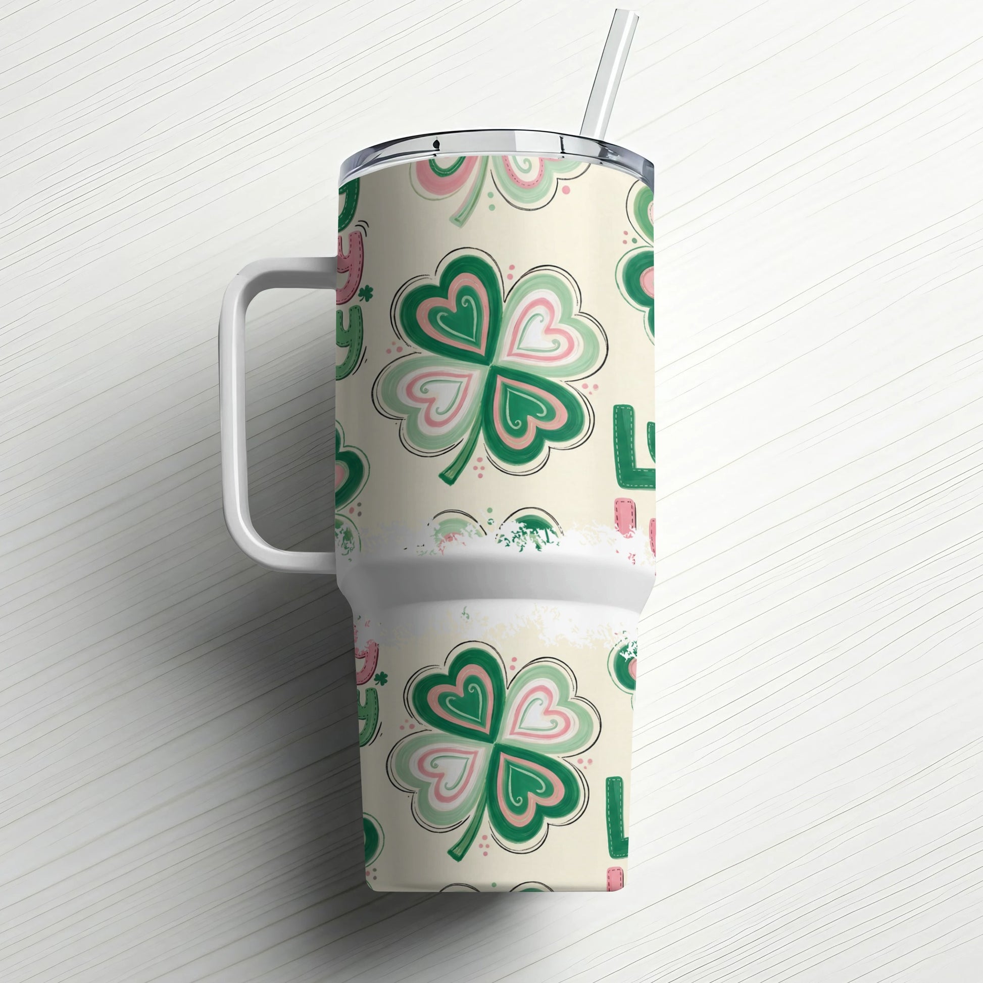 Cream tumbler with shamrock pattern and handle, straw in lid.