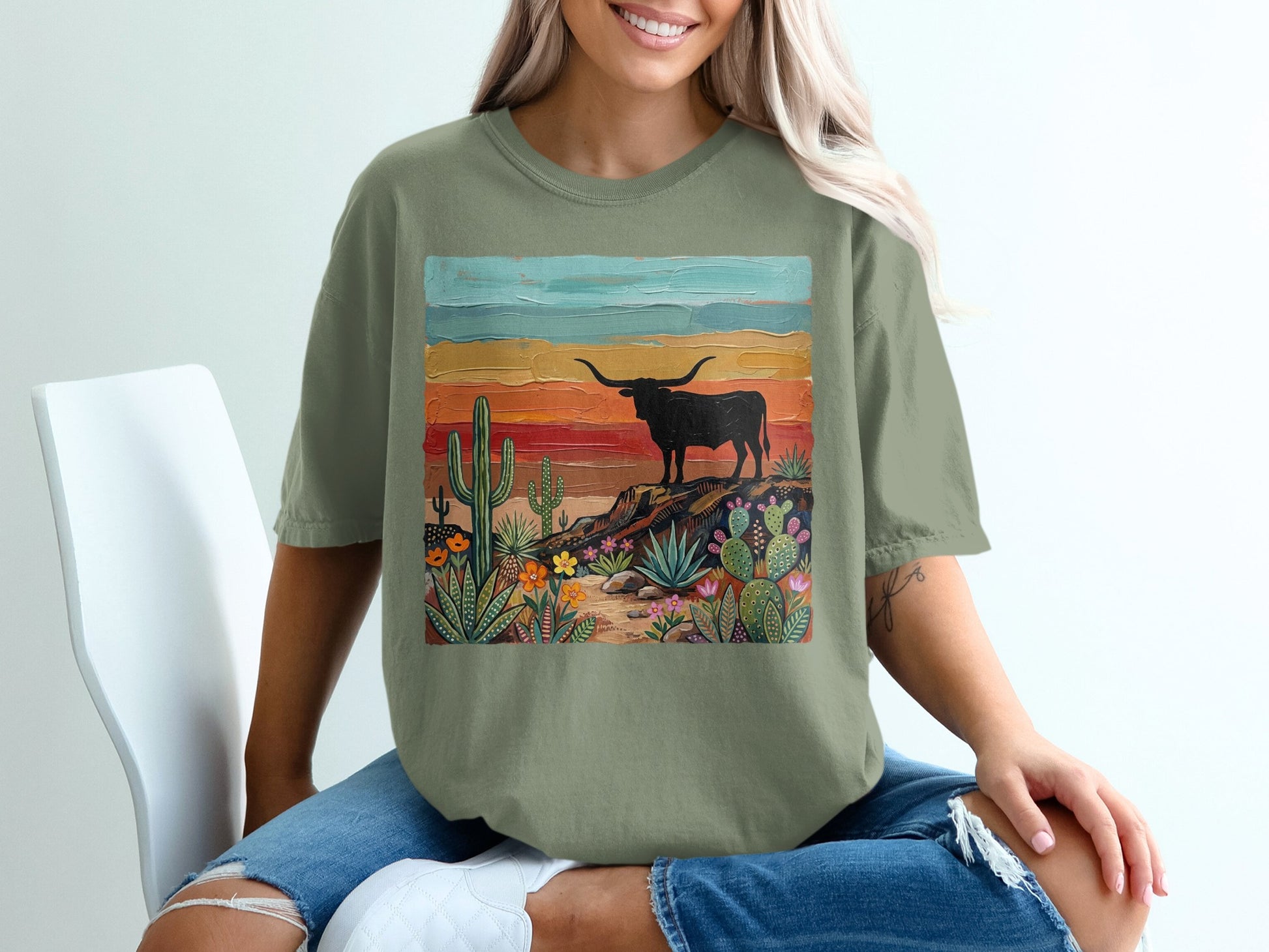T-shirt with desert landscape, longhorn steer, cacti, and colorful sunset.