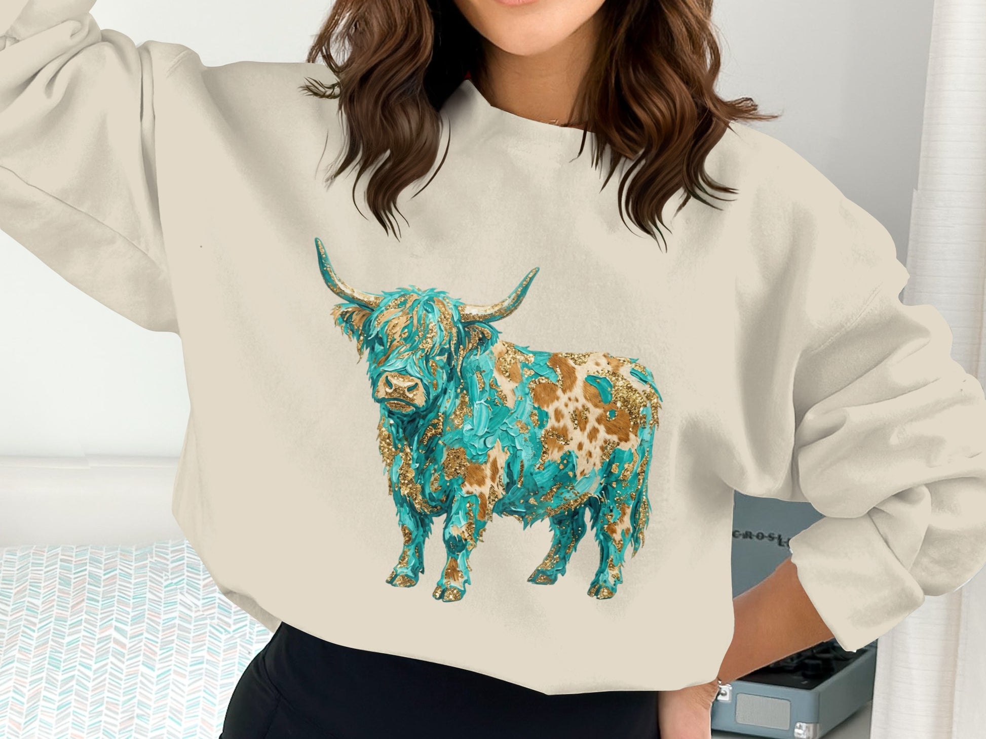 Cream sweatshirt with a stylized highland cow graphic in blue and gold.