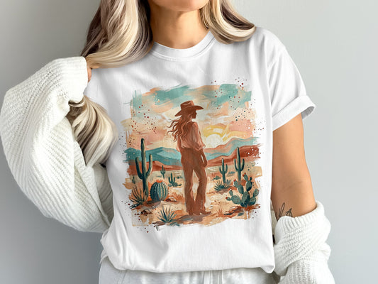 Woman in white t-shirt with desert landscape and cowboy hat graphic.