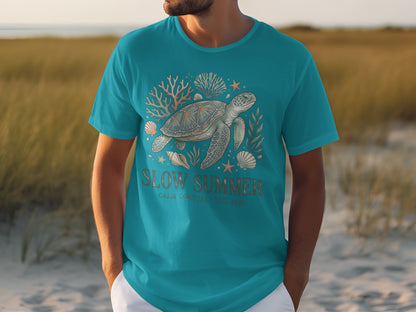 Teal t-shirt with sea turtle and coral graphic, text "SLOW SUMMER".