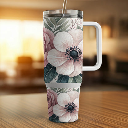 Floral tumbler with pink roses and anemones on a wooden surface.