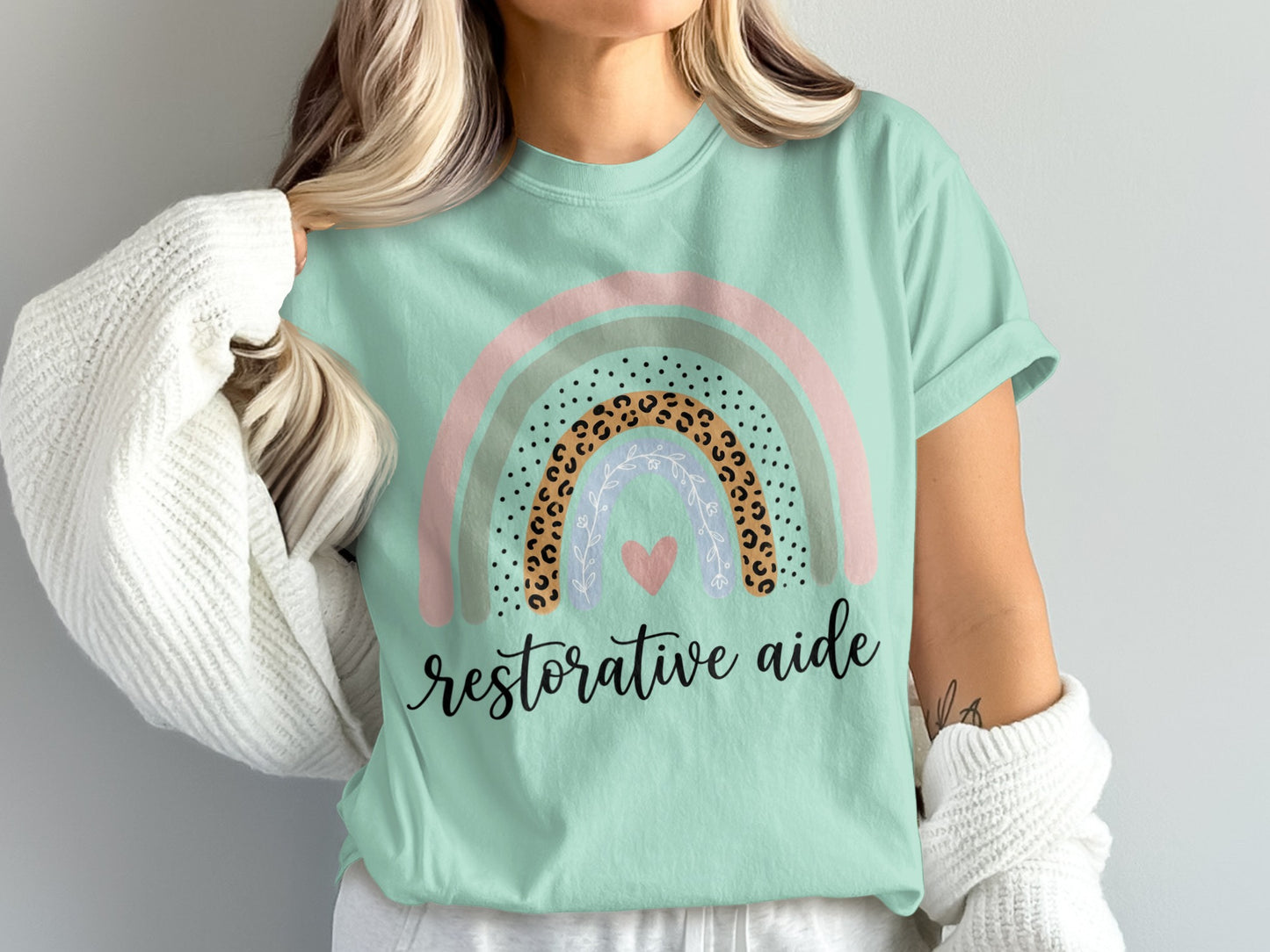 Mint t-shirt with rainbow design and "restorative aide" text.