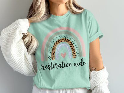 Mint t-shirt with rainbow design and "restorative aide" text.