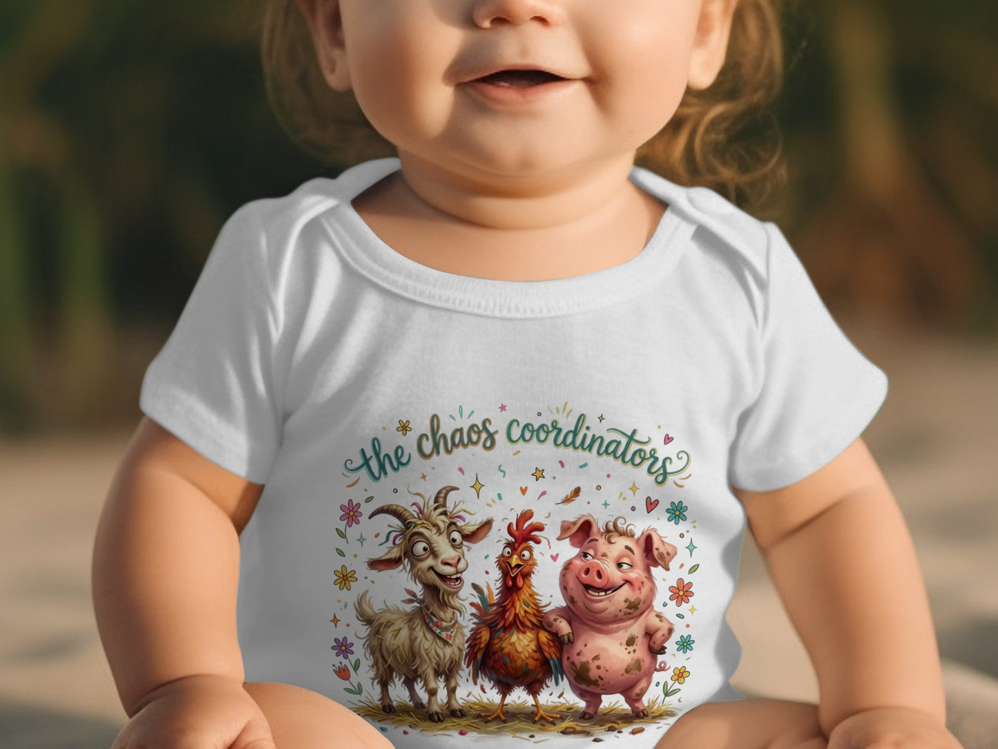 Baby in white bodysuit with "the chaos coordinators" and farm animals graphic.