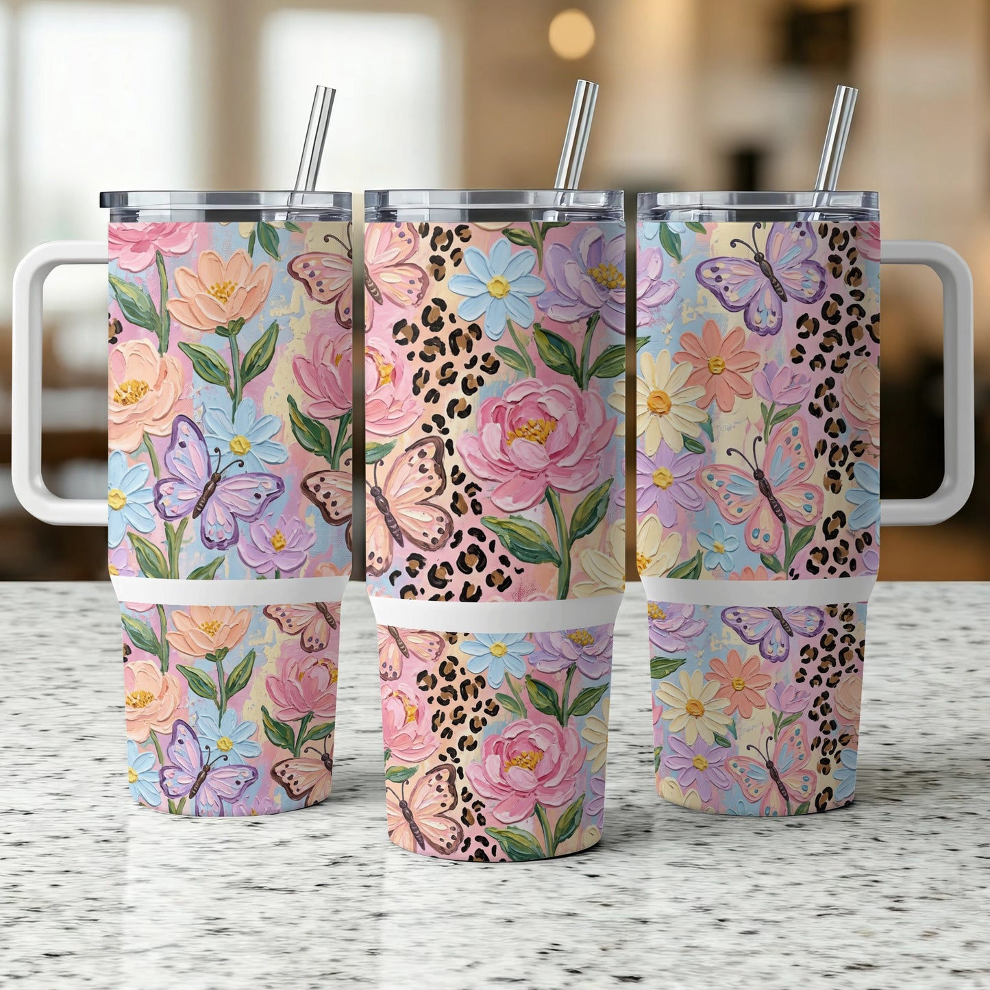 Three floral and butterfly patterned tumblers with handles and straws.