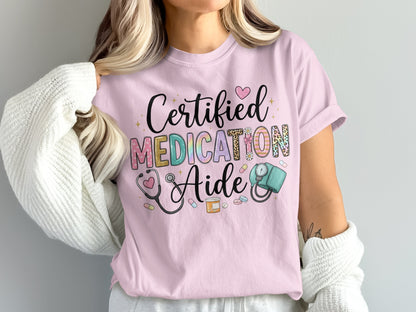 Pink t-shirt with "Certified Medication Aide" text and medical icons.