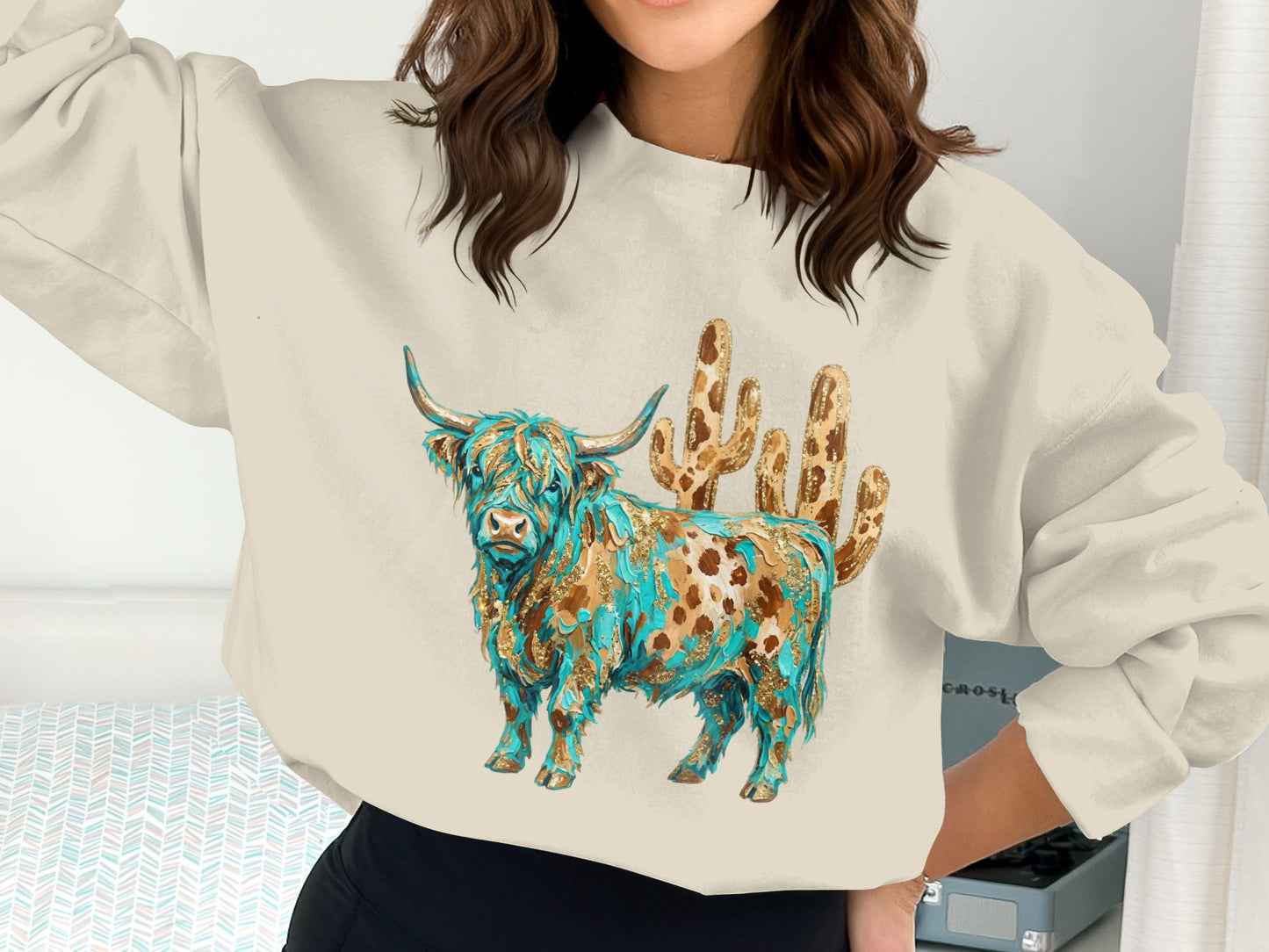Cream sweatshirt with a golden-brown Highland cow and cactus graphic.
