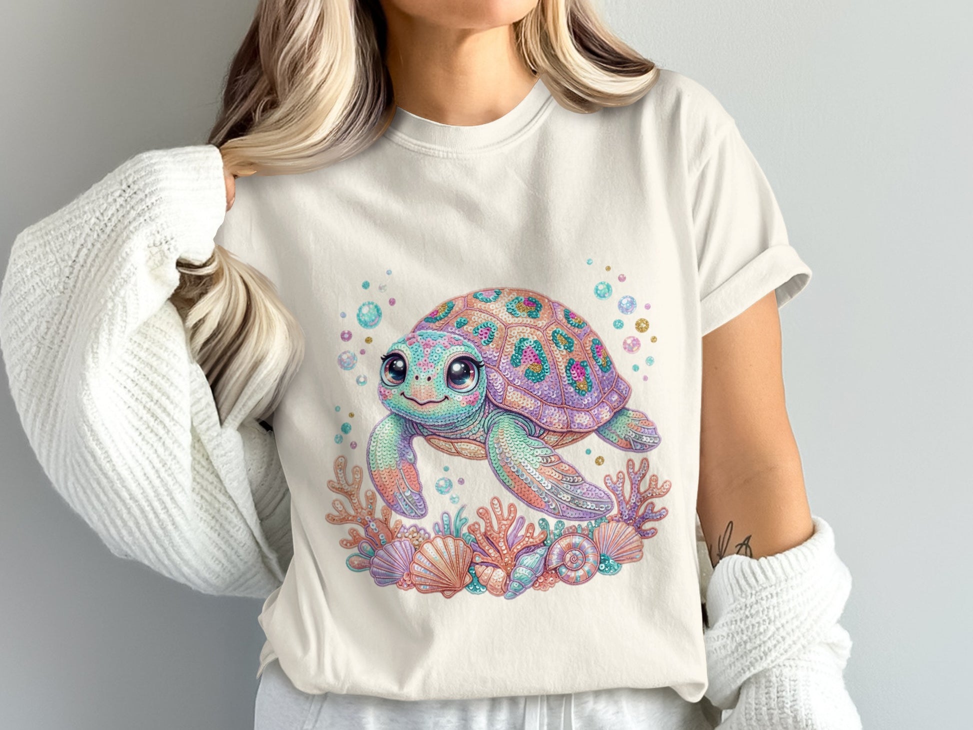 Illustrated turtle surrounded by coral and seashells on a light-colored t-shirt.