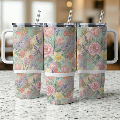 Three tumblers with pastel floral print and handles on a speckled countertop.