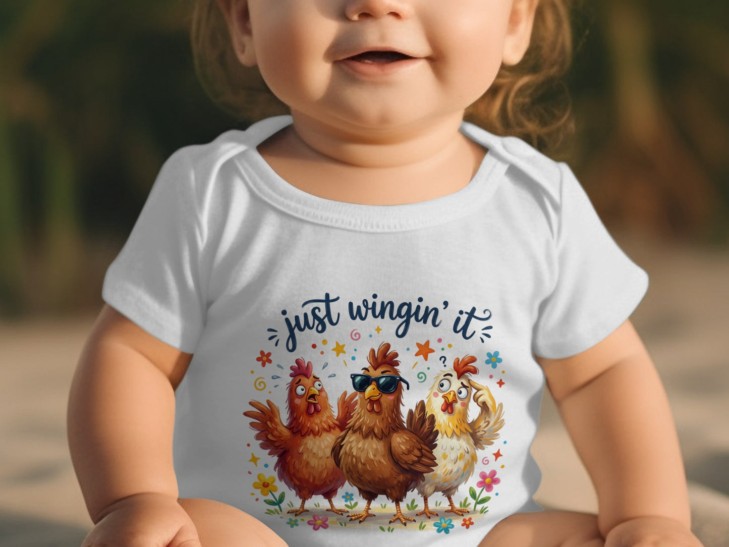 Baby in white bodysuit with three cartoon chickens saying "just wingin' it."