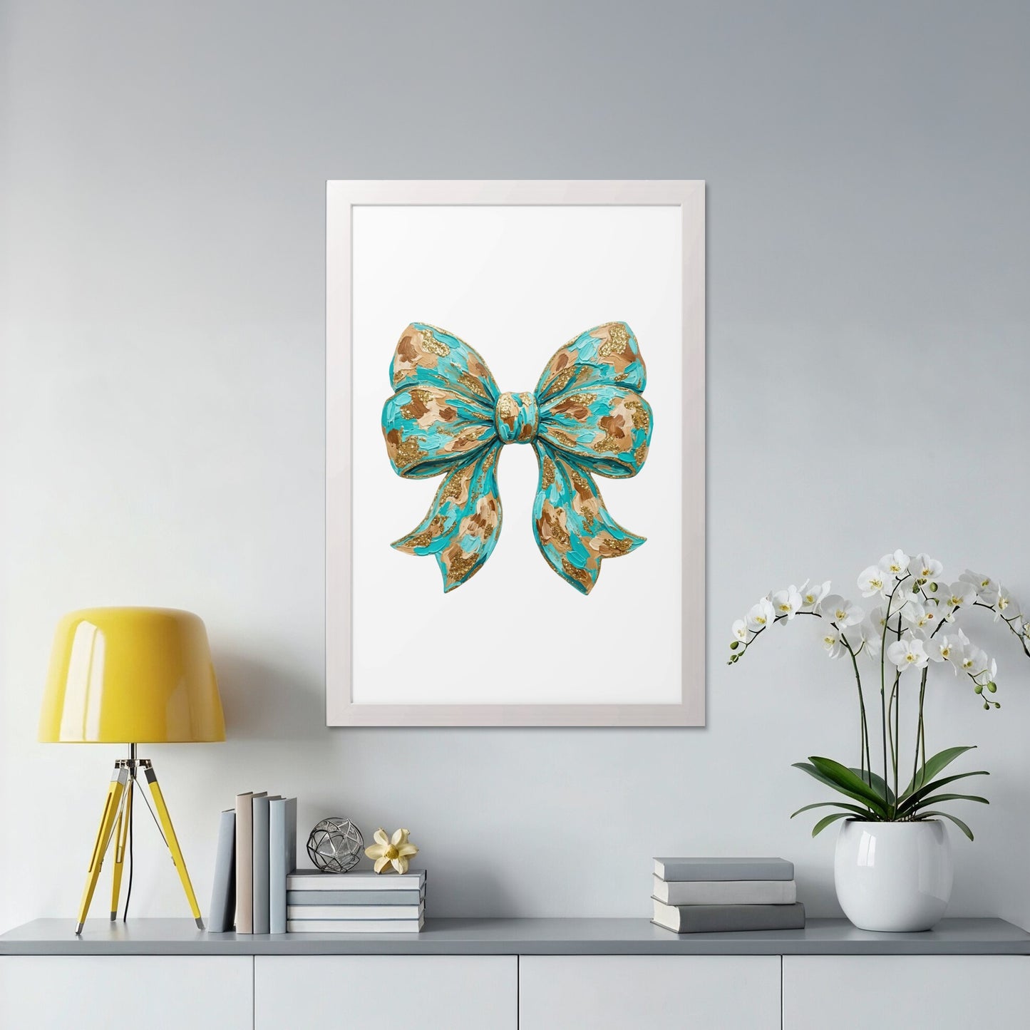 Teal and gold bow illustration in a white frame on a gray shelf.