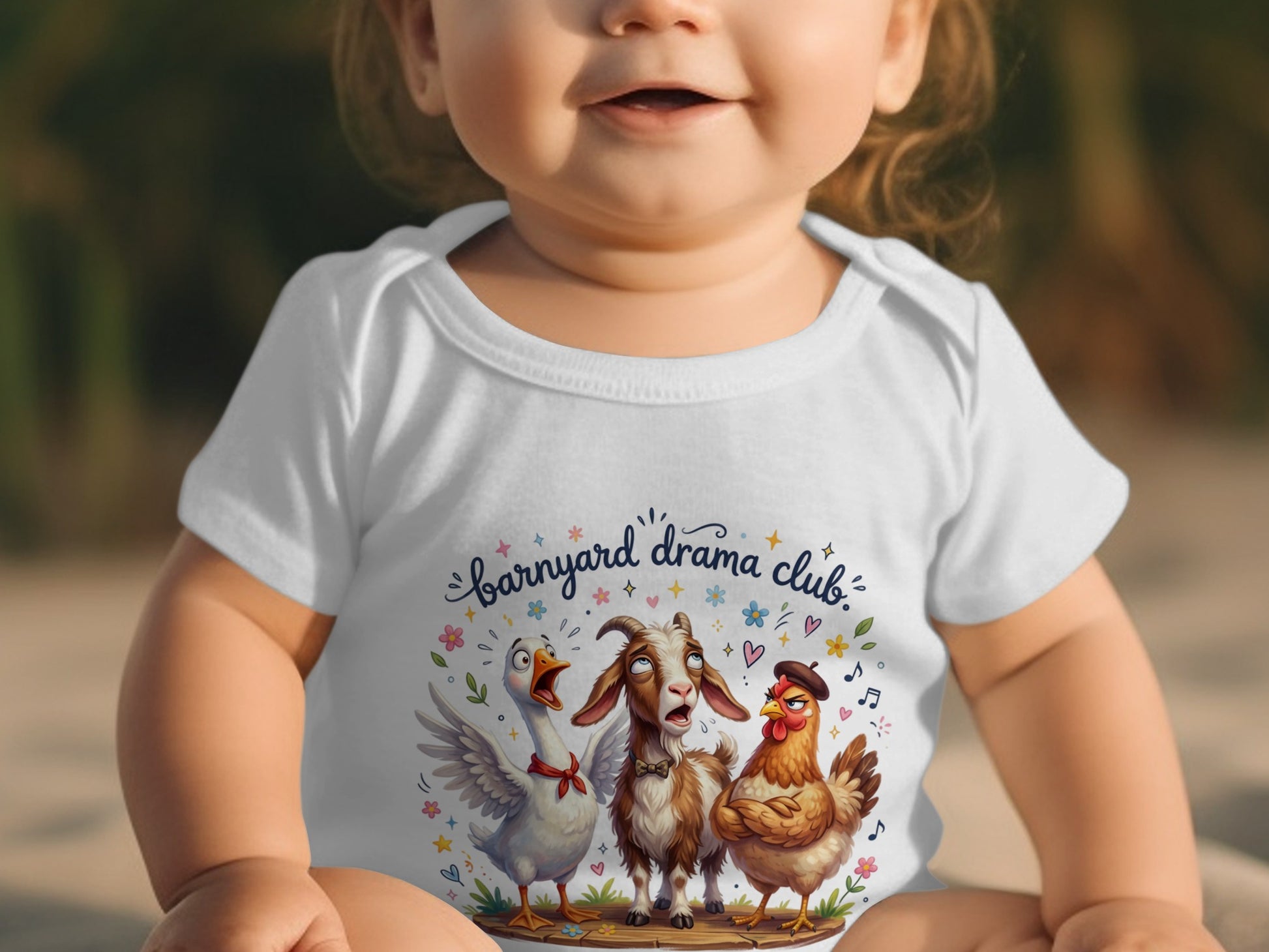 Baby wearing white bodysuit with "Barnyard Drama Club" design of duck, goat, and chicken.