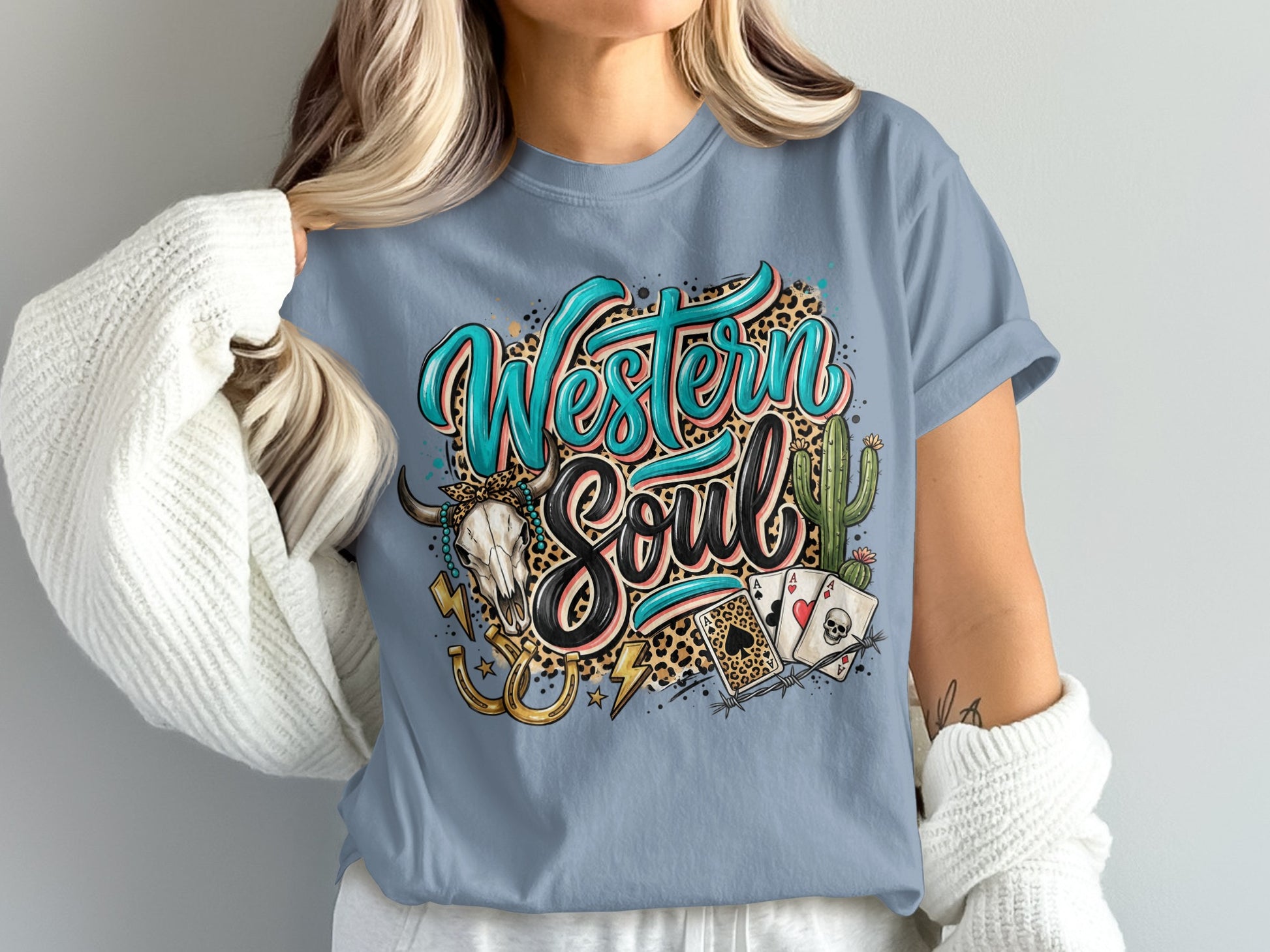 Western Soul text with skull, horseshoe, cacti, and playing cards on a blue t-shirt.
