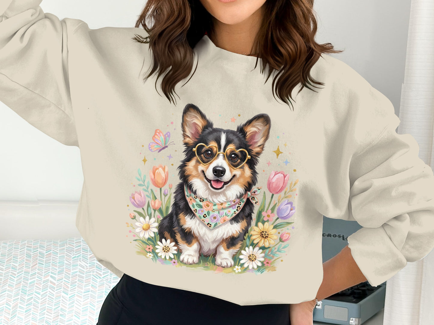 Woman wearing a sweatshirt with a corgi wearing heart glasses surrounded by flowers.