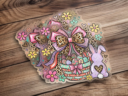 Easter basket with eggs, bow, flowers, and bunny on wood background.