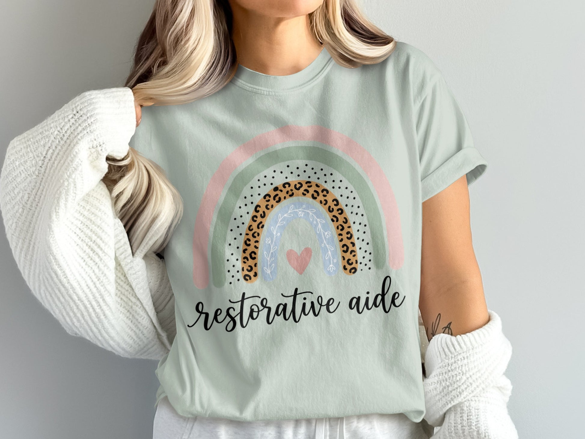 Light green t-shirt with rainbow graphic and "restorative aide" text.