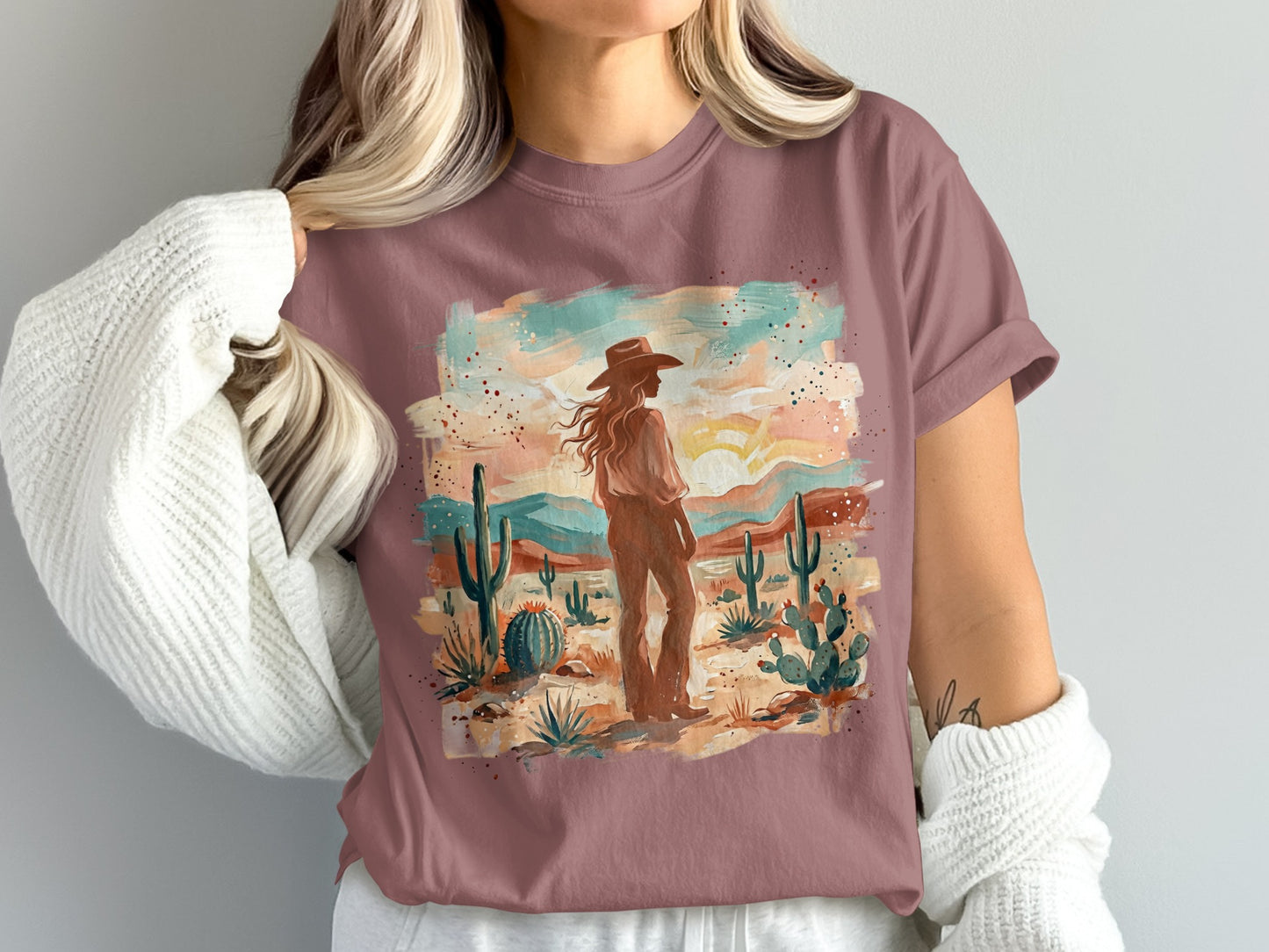 Woman in a cowboy hat stands in a desert landscape on a t-shirt.