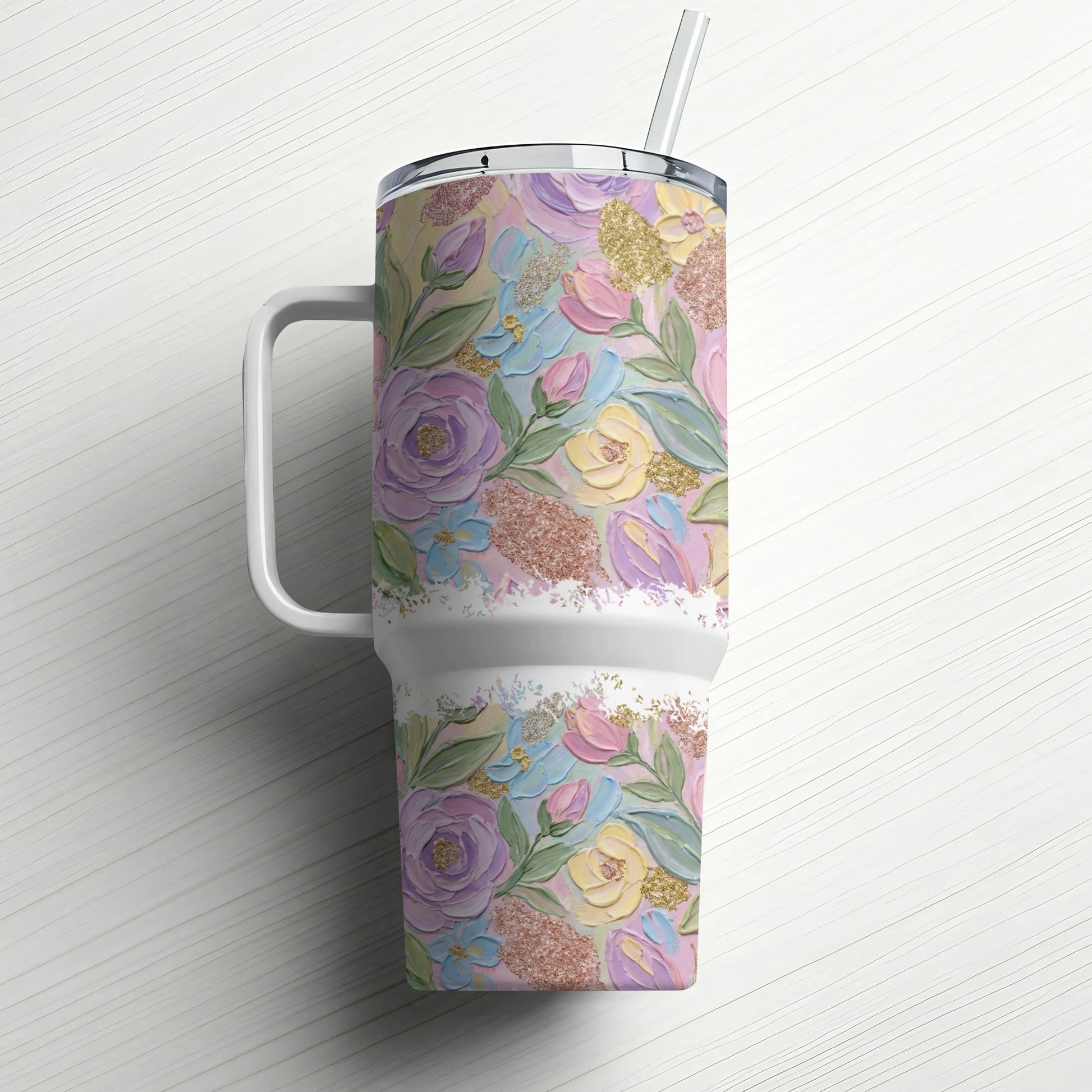 Floral textured tumbler with handle and straw on a white wooden surface.