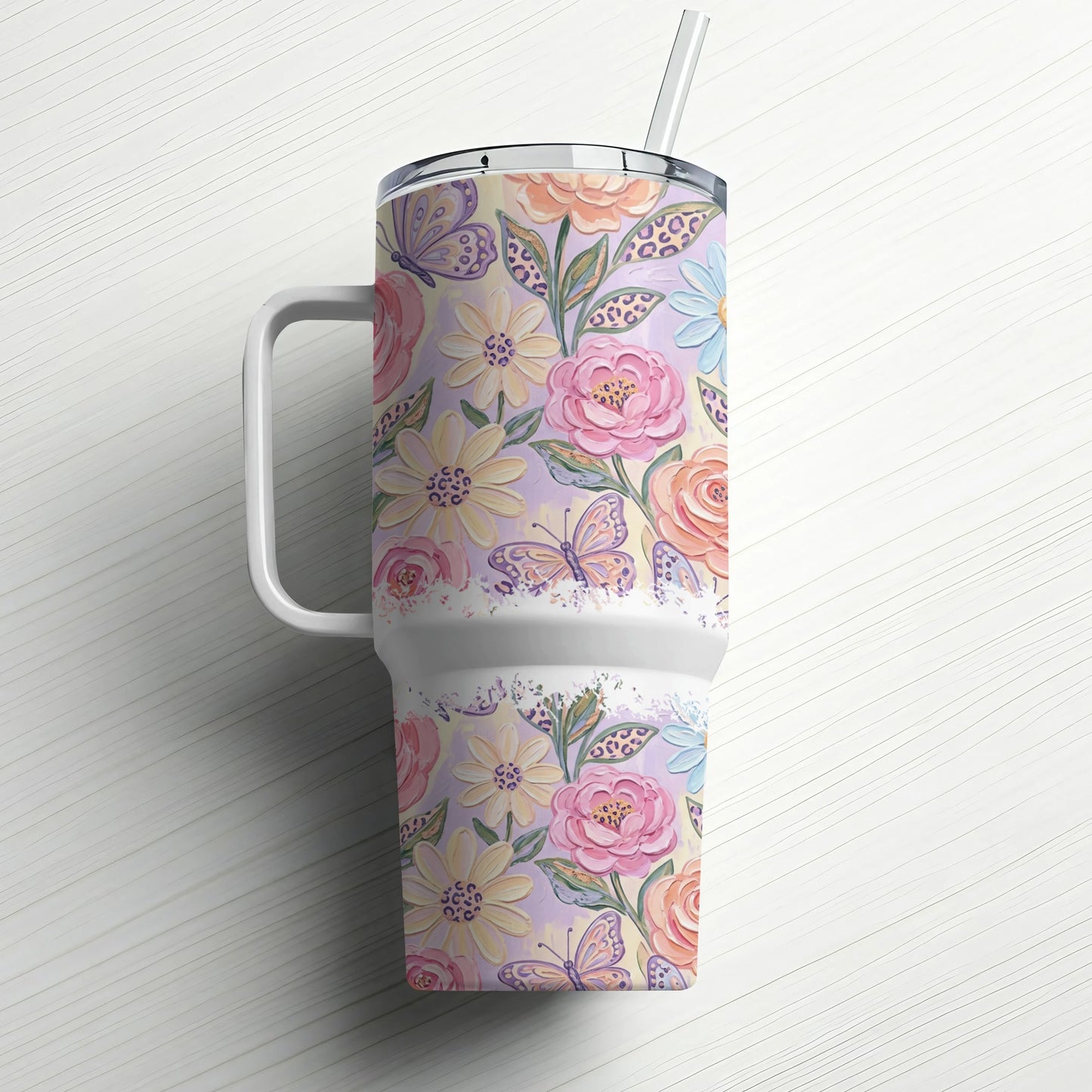 Floral and butterfly pattern tumbler with handle and straw.