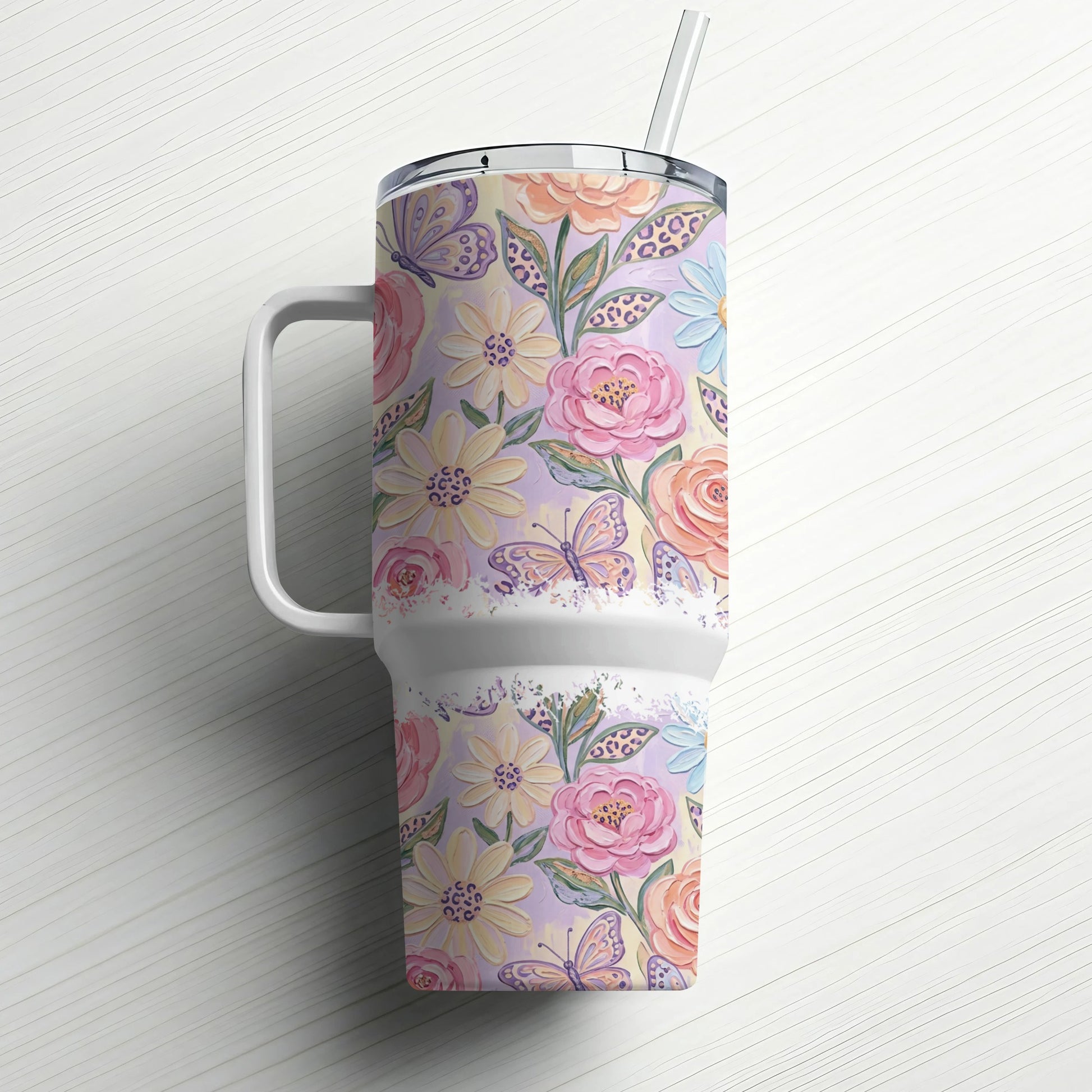 Floral and butterfly pattern tumbler with handle and straw.