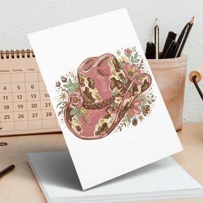 Pink and gold textured cowboy hat with floral accents on white card.
