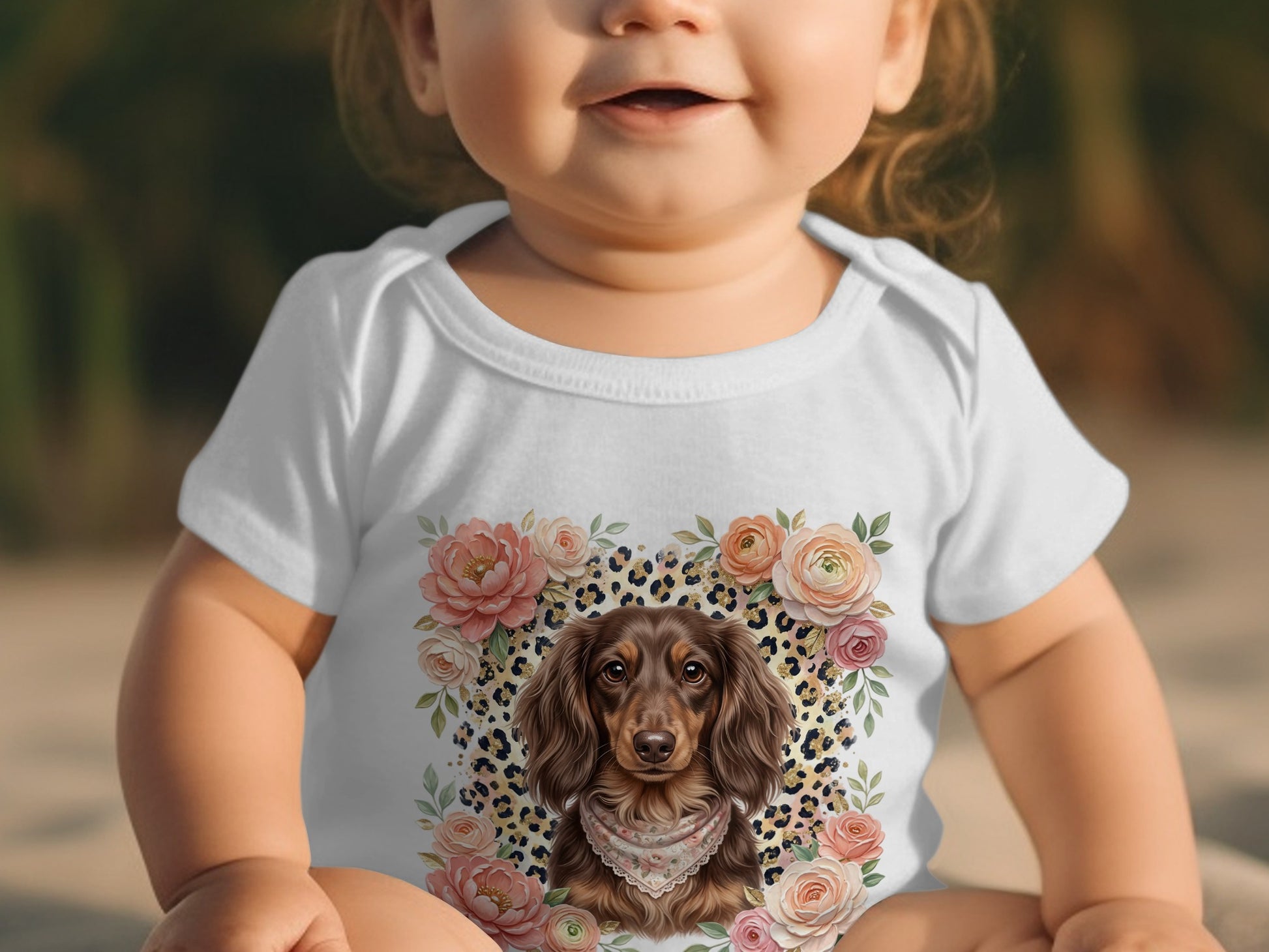 Baby wearing a white bodysuit with a long-haired dachshund and floral design.