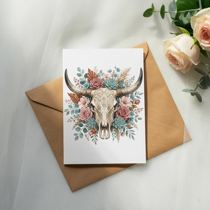 Card with floral decorated bull skull on an envelope, with roses nearby.