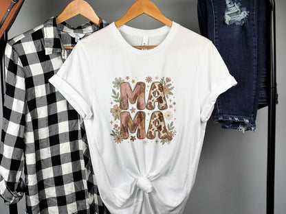 White t-shirt with "MAMA" in floral and cow print letters.