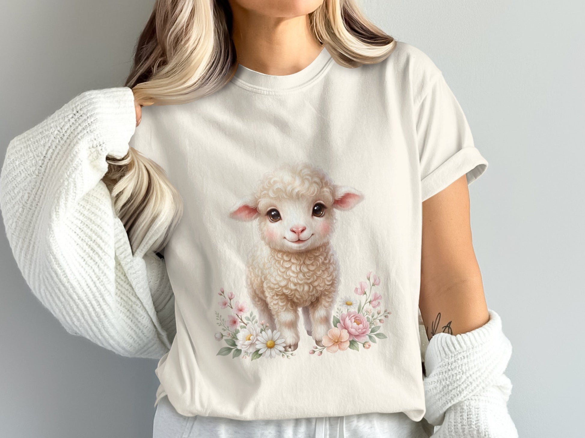 Cream t-shirt with a smiling baby sheep surrounded by pink and white flowers.