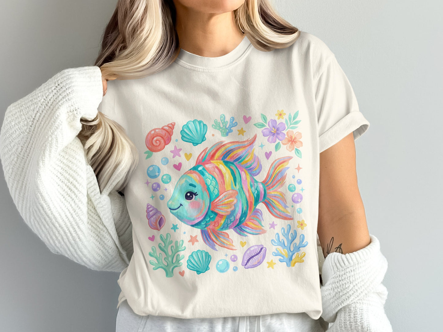 Cartoon rainbow fish surrounded by seashells, bubbles, and coral on a white t-shirt.