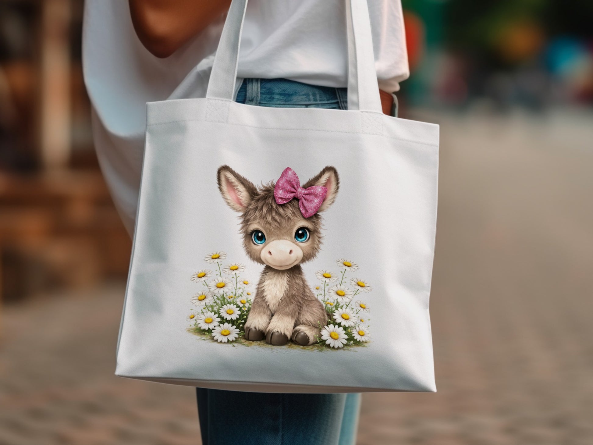 Donkey with pink bow in a field of daisies on a white tote bag.