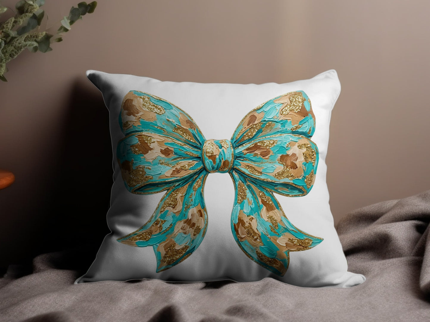 White pillow with a textured teal and gold bow design.