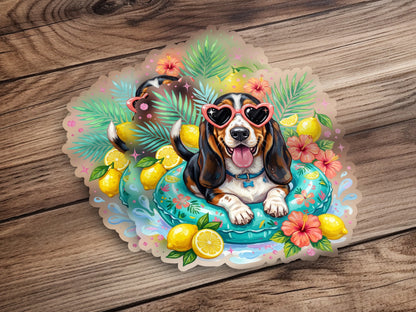 Basset hound in heart-shaped sunglasses floats on inner tube surrounded by lemons and flowers.