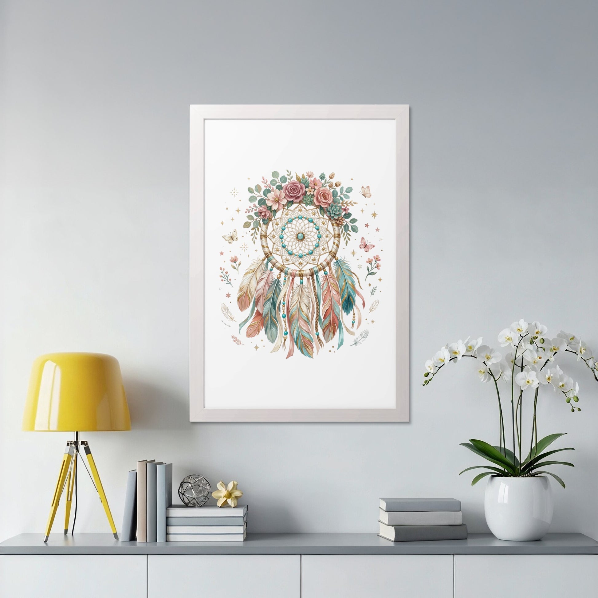 Framed dreamcatcher with floral accents hanging above a shelf with books and a lamp.